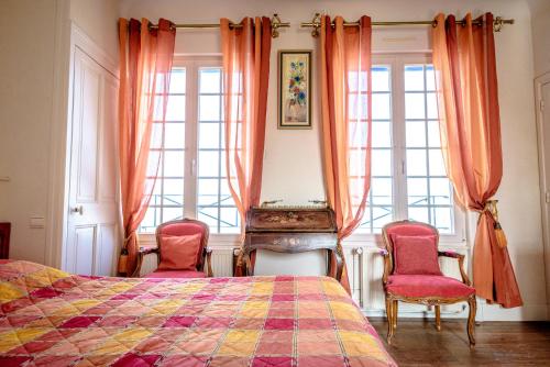a bedroom with a bed and two chairs at Maison Studios & Appartements Les 4 Vents in Luc-sur-Mer
