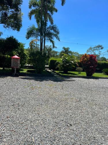 a gravel parking lot with a palm tree and bushes at Sítio Roselaine - Dream Place in Jacareí