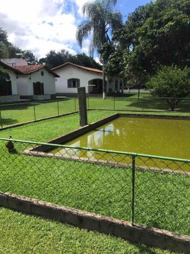 a fence in front of a pond in a yard at Sítio Roselaine - Dream Place in Jacareí