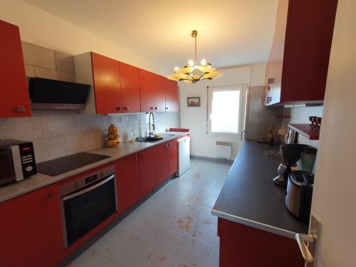 une cuisine avec des armoires rouges et un comptoir noir dans l'établissement Appartement 3 chambres avec grande terrasse dans le centre de Pernes les Fontaines, à Pernes-les-Fontaines