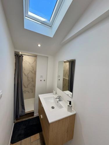 une salle de bain avec un lavabo blanc et une lucarne dans l'établissement La Cahute, à Ambleteuse