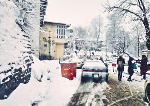 a group of people walking down a snow covered street at Grand Heights Hotel in Murree