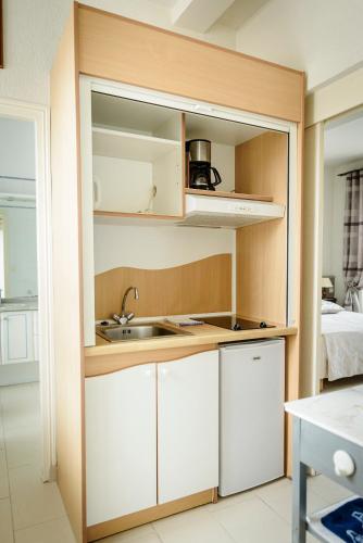 une cuisine avec des armoires blanches et un évier dans l'établissement Maison Studios & Appartements Les 4 Vents, à Luc-sur-Mer