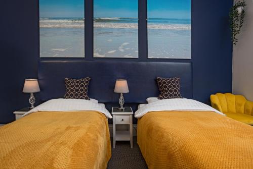 two beds in a blue room with the ocean at Glenholme Guest House - Room Only in Scarborough