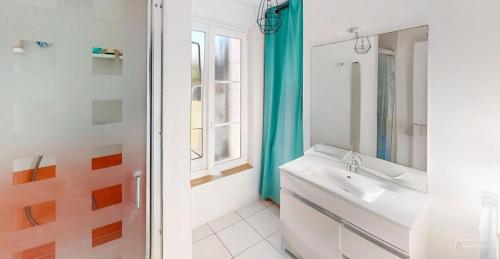 une salle de bain blanche avec un lavabo et une fenêtre dans l'établissement Le Petit Jersey, à Barneville-Carteret