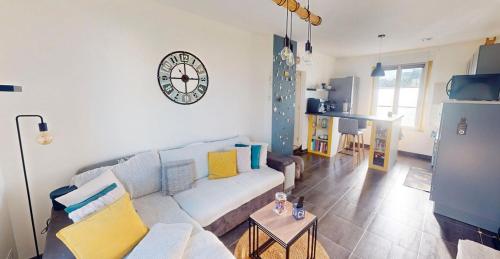 un salon avec un canapé et une horloge au mur dans l'établissement Le Petit Jersey, à Barneville-Carteret