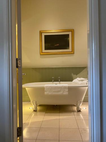 a white bath tub in a bathroom with a picture at The Punch Bowl Inn in Kendal