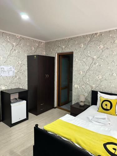 a bedroom with a bed with a yellow blanket at Aura Plaza Hotel in Tbilisi City