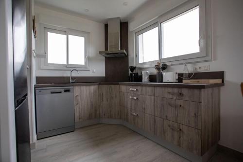 - une cuisine avec des placards en bois et 2 fenêtres dans l'établissement Dunes d'Hattainville, à Les Moitiers-dʼAllonne