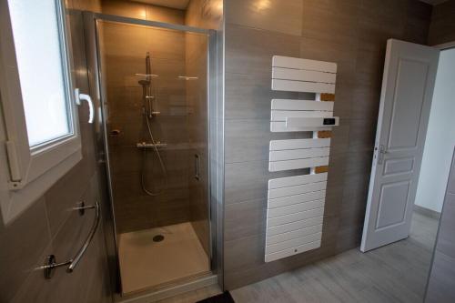 une salle de bain avec une douche avec une porte vitrée dans l'établissement Dunes d'Hattainville, à Les Moitiers-dʼAllonne