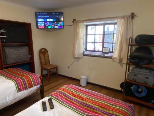 a bedroom with a bed and a tv on the wall at Casa Cusco Centro in Cusco