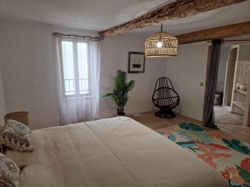 a bedroom with a large bed and a chandelier at Maison de charme et vue Imprenable à 180 degrés sur les vignes et Pyrénées in Paraza