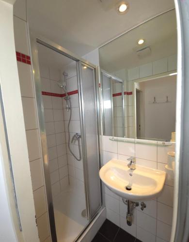 a bathroom with a sink and a shower with a mirror at Aparthotel Amelie in Vienna