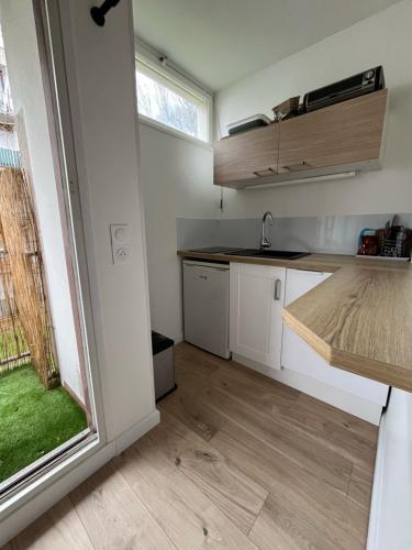 une cuisine avec des armoires blanches, un évier et une fenêtre dans l'établissement Les Tulipiers, à Nantes