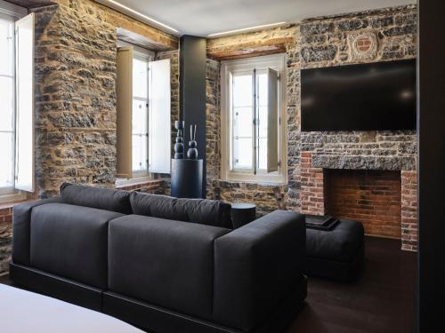 a living room with a black couch and a fireplace at Hôtel Maison du Fort in Quebec City