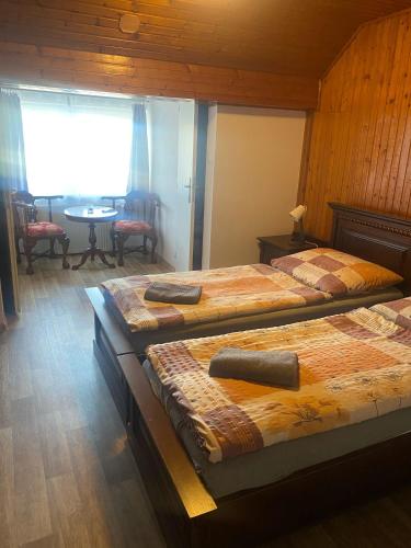 a room with three beds and a table with a window at Penzion U Jandů in Běhařov