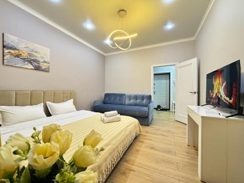 ein Schlafzimmer mit einem Bett und einer blauen Couch in der Unterkunft Новая квартира рядом с ЭКСПО АЭРОПОРТОМ ПРЕЗИДЕНТСКАЯ БОЛЬНИЦА Венский 29б in Astana