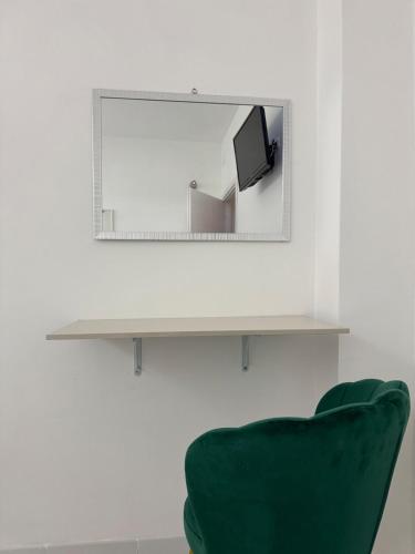 a mirror hanging on a wall next to a green chair at Soffio di mare Apartment in Stazione di Montenero-Petacciato