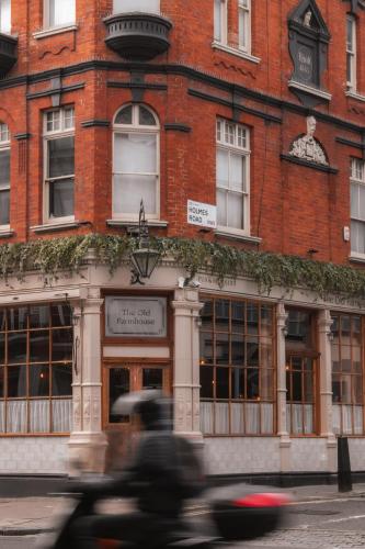 a person riding a motorcycle in front of a building at The Old Farmhouse Pub and Rooms in London