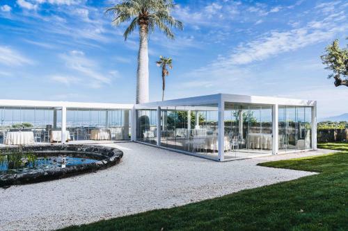 a large white building with a palm tree in the background at Park Hotel Villa Grazioli in Grottaferrata