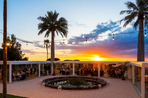 a group of people standing outside of a building with a sunset at Park Hotel Villa Grazioli in Grottaferrata
