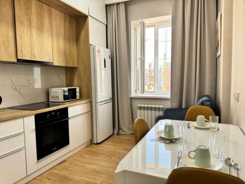 eine Küche mit einem Tisch und einem weißen Kühlschrank in der Unterkunft Новая квартира рядом с ЭКСПО АЭРОПОРТОМ ПРЕЗИДЕНТСКАЯ БОЛЬНИЦА Венский 29б in Astana