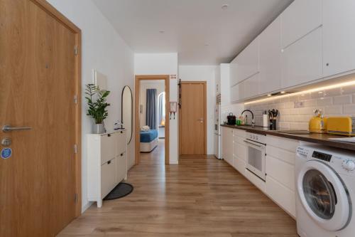 a kitchen with white cabinets and a washer and dryer at Lush Botanic Oasis with a Boho Hideaway, Near Beach & Cafés in Lagos