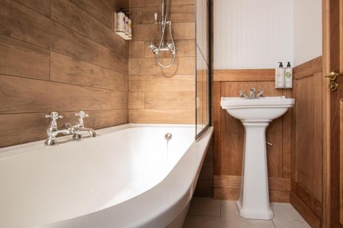 a bathroom with a white tub and a sink at The Old Farmhouse Pub and Rooms in London