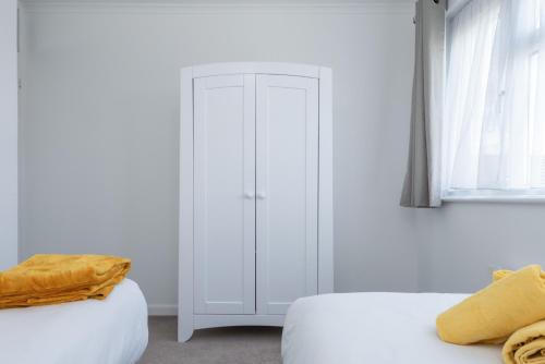 a bedroom with two beds and a white cabinet at Spacious 2BR home in Croydon with parking in Wallington