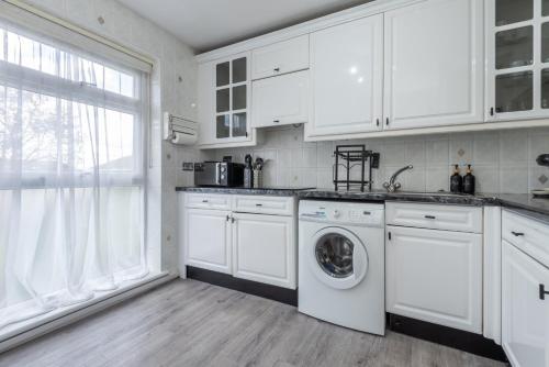 a kitchen with white cabinets and a washer and dryer at Spacious 2BR home in Croydon with parking in Wallington