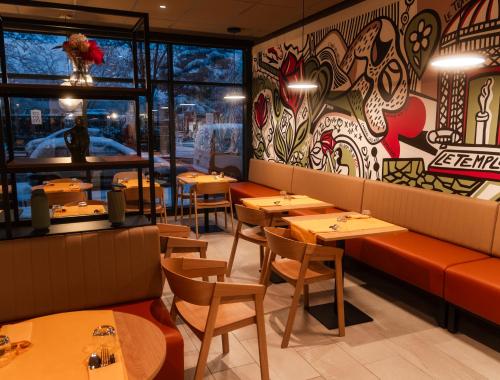 un restaurant avec des tables et des chaises et un mur de fenêtres dans l'établissement Résidence CAZAM L'HAY LES ROSES, à Chevilly-Larue