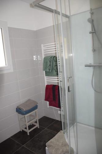 La salle de bains est pourvue d'une douche, d'un tabouret et de serviettes. dans l'établissement Charmante maison à Souvigny avec jacuzzi, à Souvigny