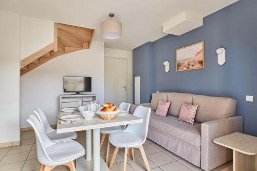 a living room with a couch and a table and chairs at Résidence Odalys Le Mas des Flamants in Aigues-Mortes