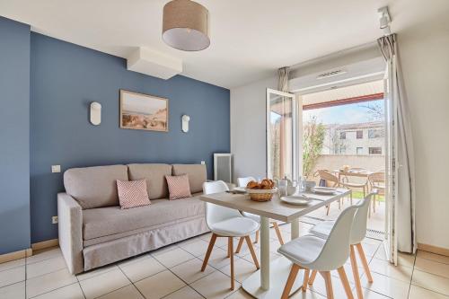 a living room with a couch and a table at Résidence Odalys Le Mas des Flamants in Aigues-Mortes