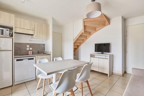 a kitchen and dining room with a table and chairs at Résidence Odalys Le Mas des Flamants in Aigues-Mortes