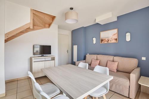a living room with a table and a couch at Résidence Odalys Le Mas des Flamants in Aigues-Mortes