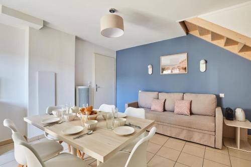 a dining room with a table and a couch at Résidence Odalys Le Mas des Flamants in Aigues-Mortes