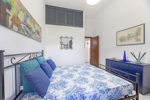 a bedroom with a bed with blue pillows and a dresser at Fiori di Mare in Le Foci