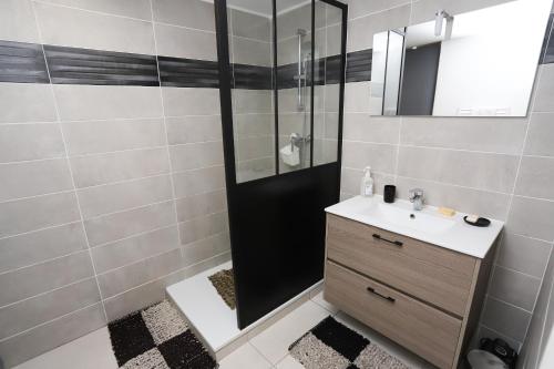 une salle de bain avec une douche avec un lavabo et un miroir dans l'établissement Appart lumineux et climatise St Cyprien plage, à Saint-Cyprien