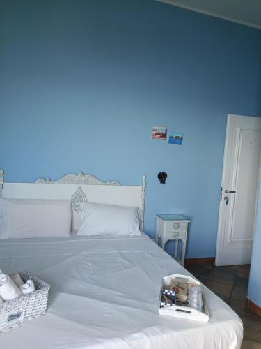 a bedroom with a white bed with a blue wall at Case Nereidi 2 in Porticello