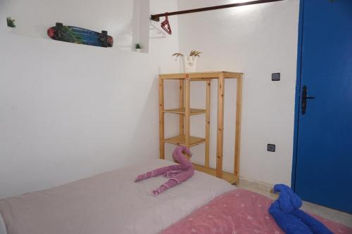 a room with a bed with a pink stuffed animal on it at Hostel The Endless House Anchor point in Taghazout