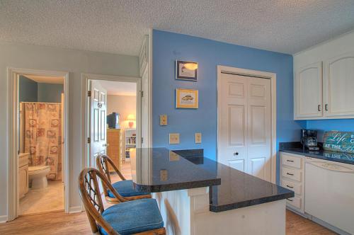 a kitchen with blue walls and a black counter top at Sands V A3 by Carolina Beach Realty in Carolina Beach