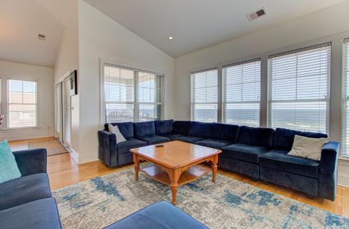 een woonkamer met een blauwe bank en een tafel bij Sandstep by Carolina Beach Realty in Carolina Beach