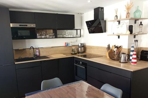 une cuisine avec des armoires noires et une table en bois dans l'établissement Apartment of 60 m2 near the beach of Le Touquet, à Le Touquet-Paris-Plage
