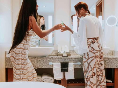 马霍礁Sonesta Ocean Point Resort- All Inclusive - Adults Only的女人站在浴室镜子前