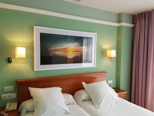 a bedroom with a bed with a picture on the wall at Hotel Faro de San Vicente in San Vicente de la Barquera