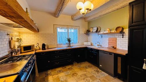 a kitchen with black cabinets and a stove top oven at Le Beldi, Mas de Village 1870 in Saint-Saturnin-lès-Avignon