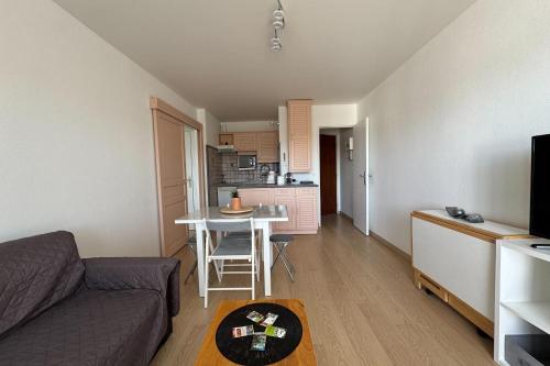 un salon avec un canapé et une table et une cuisine dans l'établissement Accommodation near the beach - Courseulles-sur-Mer, à Courseulles-sur-Mer