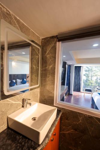 a bathroom with a sink and a large mirror at White Castle Himalayan View by Lavender Hotels in Shimla