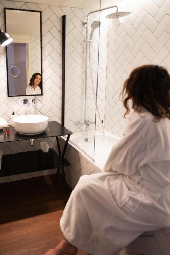 a woman sitting in front of a sink in a bathroom at Aiden by Best Western Lorient Centre in Lorient